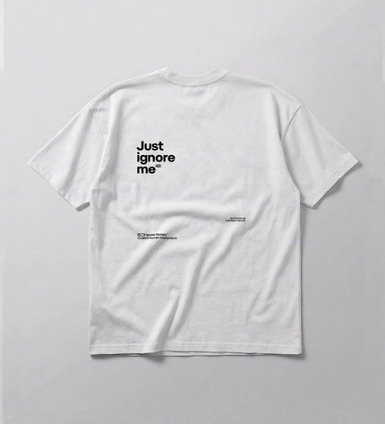 White t-shirt with 'Just ignore me' text on a gray background