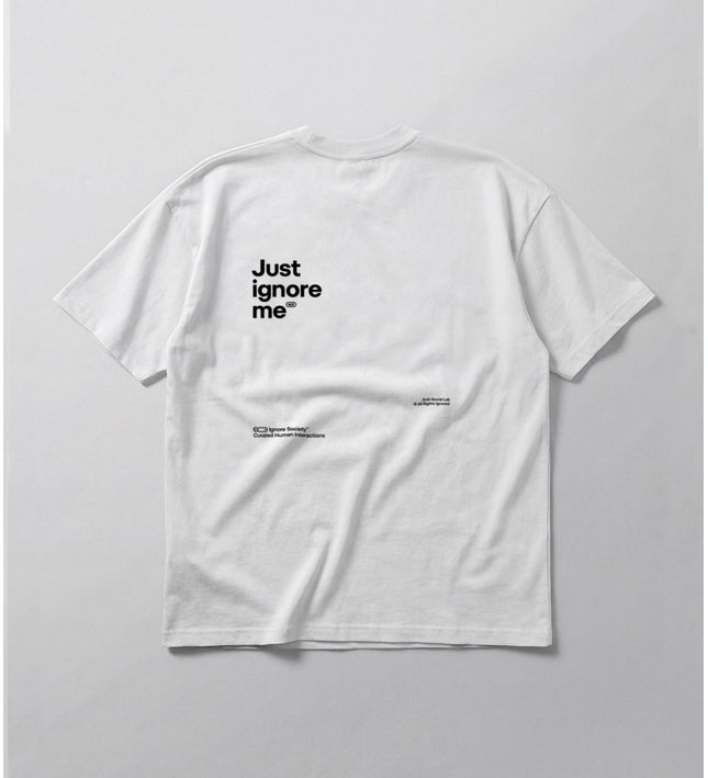 White t-shirt with 'Just ignore me' text on a gray background