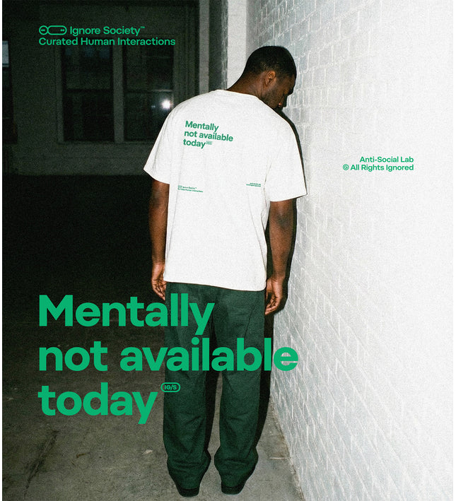 Person wearing a white t-shirt with 'Mentally not available today' text, leaning against a wall.