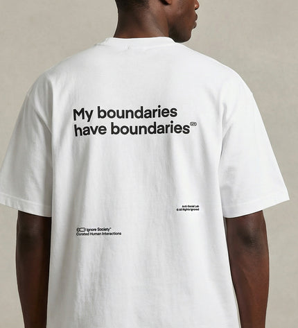 Person wearing a white t-shirt with text on the back, standing against a neutral background