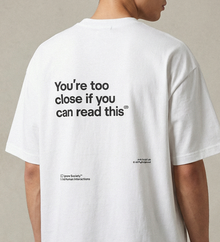 White t-shirt with humorous text on the back, worn by a person against a neutral background